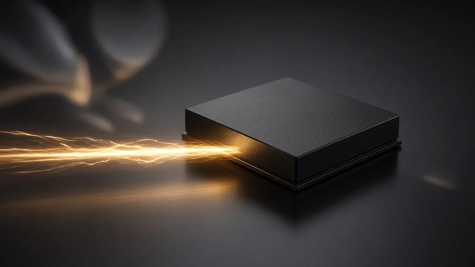A matte black chip on a dark reflective surface with a streak of amber light racing into it